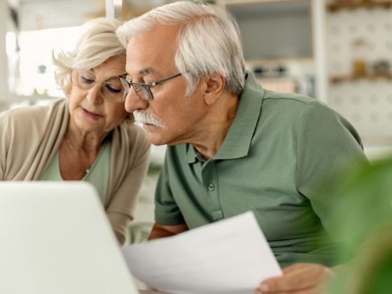 Casal de idosos consulta documentos e notebook para verificar pagamento de atrasados do INSS