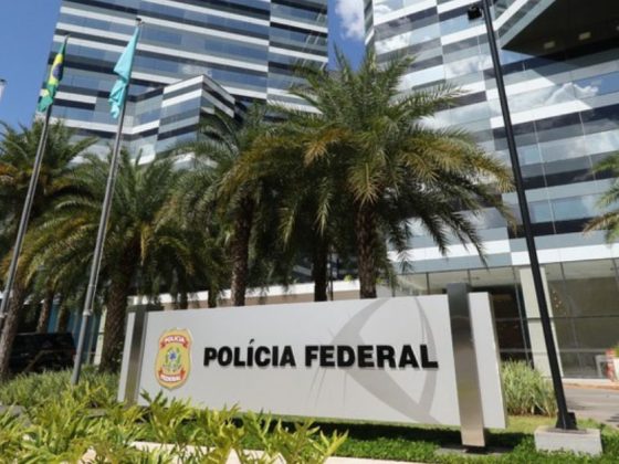 Fachada da sede da Polícia Federal em Brasília, órgão responsável pela Operação Disclosure, com placa institucional em primeiro plano e edifício espelhado ao fundo