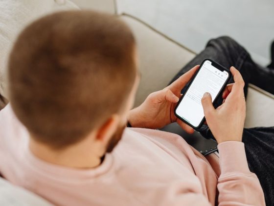 Homem deitado no sofá lendo SMS sobre IPVA 2026 atrasado no celular