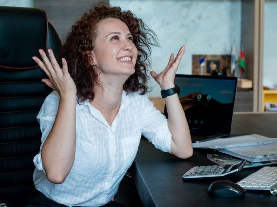 Mulher comemorando restituição do IR sentada em frente ao computador no escritório