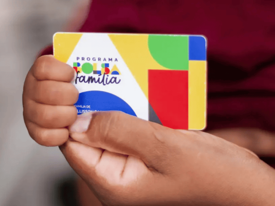 Duas mãos segurando o cartão do Bolsa Família