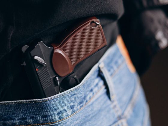 porte de arma tucado na cintura de uma pessoa vestindo calça jeans
