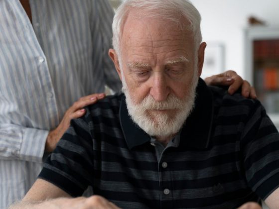Idoso com Alzheimer monta quebra-cabeça com apoio de cuidador