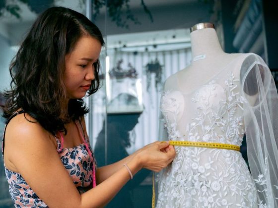 Mulher medindo vestido em manequim em ateliê, ilustrando o Programa Mulher Empreendedora em BH