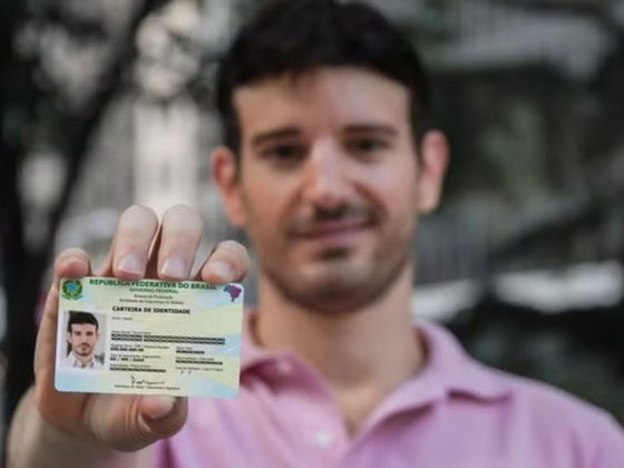 Homem segurando a Carteira de Identidade Nacional em Minas Gerais com o documento em destaque
