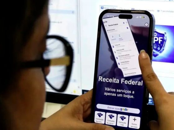 Mulher consulta aplicativo da Receita Federal no celular para verificar restituição do Imposto de Renda 2026