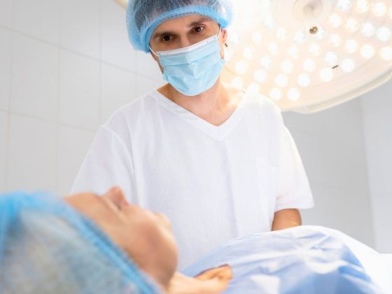 Médico em centro cirúrgico ao lado de paciente representando paciente que perdeu umbigo em procedimento que gerou indenização por cirurgia estética em MG