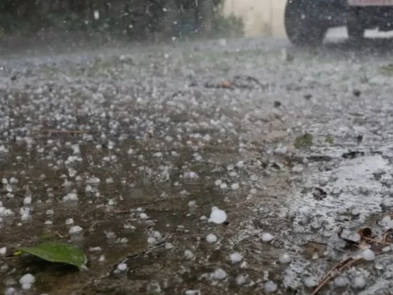 Pedras de granizo em Minas Gerais acumuladas no chão durante tempestade com carro ao fundo