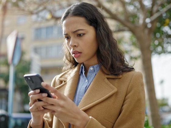 Mulher lê alerta por SMS de pessoas desaparecidas no celular em via pública