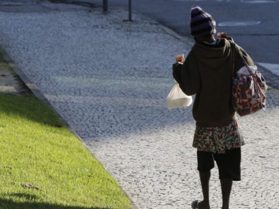 Pessoa em situação de rua caminha de costas por calçada, representando o público atendido pelo programa de dependentes químicos de Montes Claros