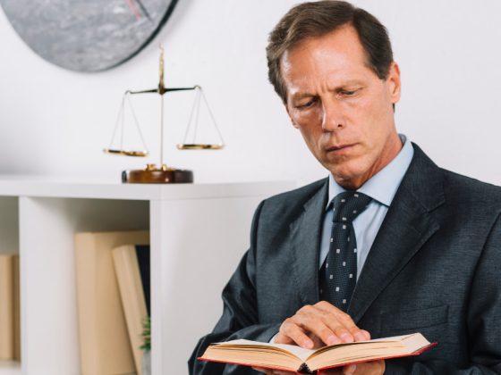 Promotores de MG: advogado de terno lê livro jurídico em tribunal