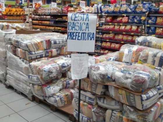 Cestas básicas do Programa Cesta nas Férias empilhadas em supermercado de Belo Horizonte