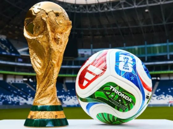 Bola inteligente da Copa do Mundo 2026, a Trionda, ao lado do troféu da FIFA em estádio