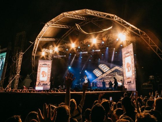 Palco iluminado com público em show — cachê de artistas pago com dinheiro público tem teto em MG