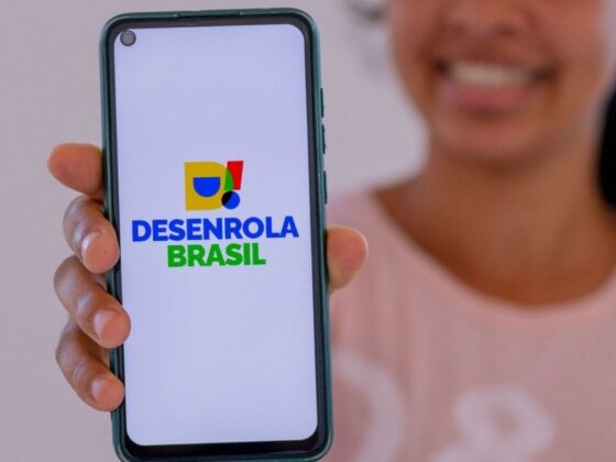 Mulher segura celular com a tela exibindo o logotipo do Novo Desenrola Brasil