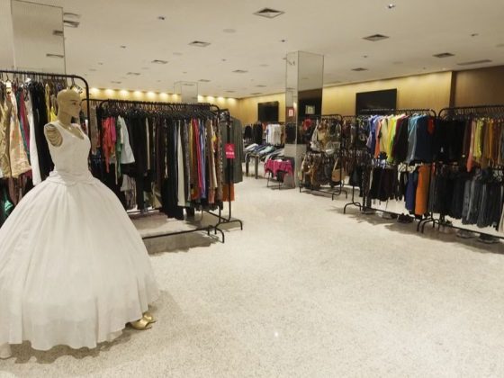 Araras com roupas variadas e manequim com vestido de noiva no Bazar do Bem em BH