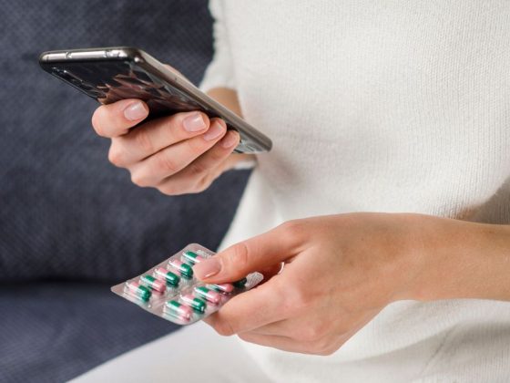 Mulher segura cartela de remédios e celular, ilustrando a venda de remédios na Shopee
