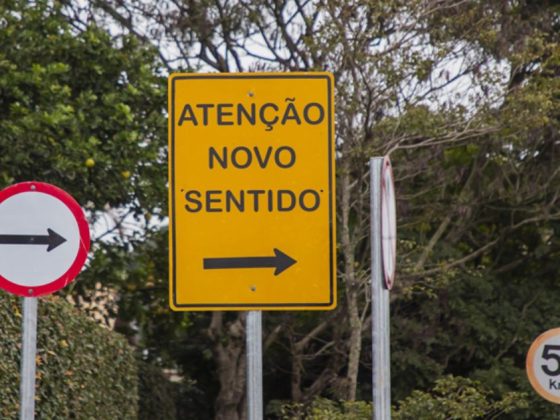 Placa amarela de sinalização indicando novo sentido em rua com mão única em Belo Horizonte