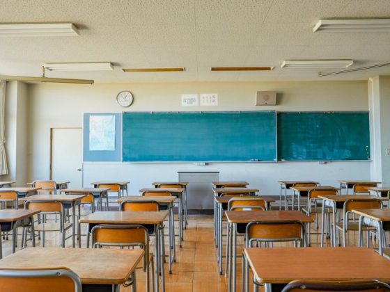 Sala de aula vazia com carteiras organizadas, quadro-negro ao fundo, ilustrando o impacto das demissões de profissionais de apoio escolar em BH.