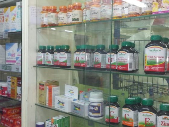 Prateleiras com medicamentos e suplementos em uma farmácia, representando o sistema da Farmácia de Minas e o acesso de pacientes a tratamentos pelo SUS.