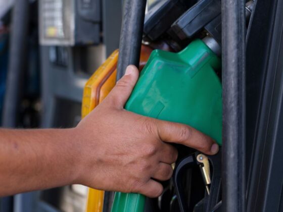 Mão segurando bico de abastecimento em posto de gasolina, representando a mudança no preço dos combustíveis
