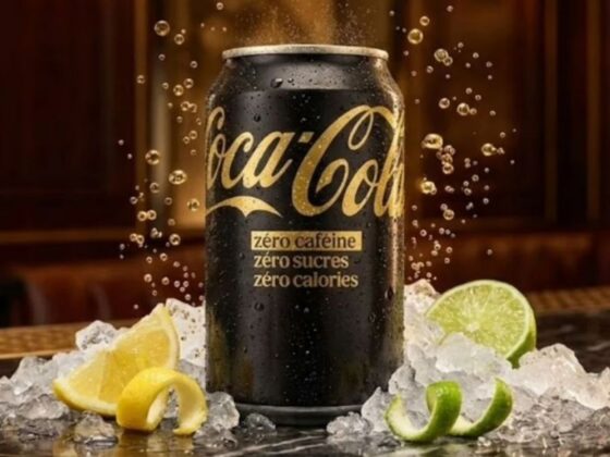 Lata preta e dourada da Coca-Cola Zero Cafeína sobre gelo, com fatias de limão ao redor