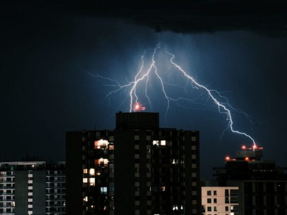 Raios caem sobre prédios durante tempestade à noite, representando os riscos do ciclone extratropical em Minas Gerais