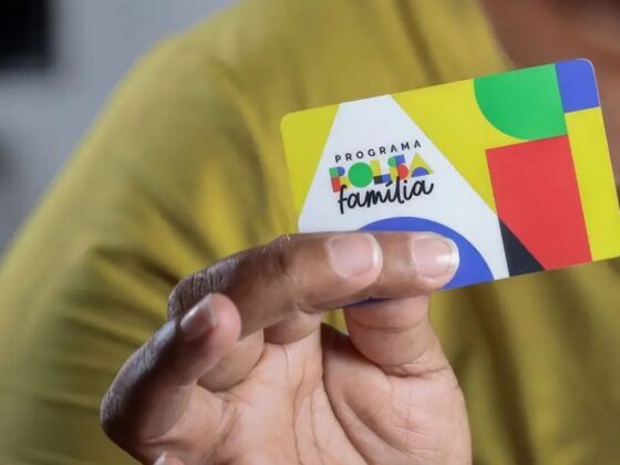 Mão segurando cartão do Bolsa Família com carteira assinada