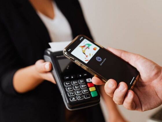 Pessoa pagando com celular em maquininha, prática relacionada à consumação mínima obrigatória em casas noturnas