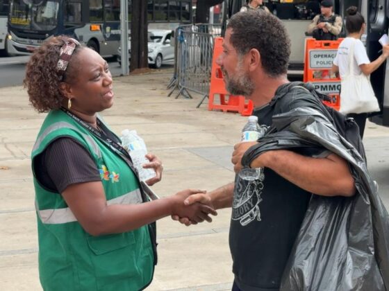 Agente da PBH entrega água a morador de rua durante onda de calor em BH, na Praça da Estação