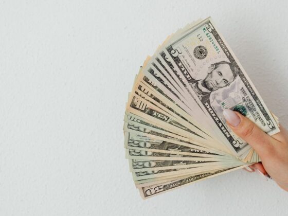 Pessoa segurando notas americanas, representando a alta do dólar.