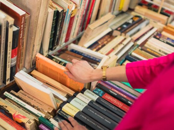 Mulher folheia livros em estantes durante liquidação de livros na Savassi