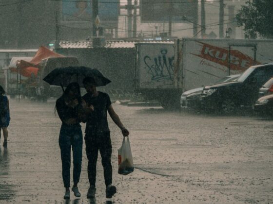 Pessoas se protegendo da chuva, representando a chegada da frente fria em BH.