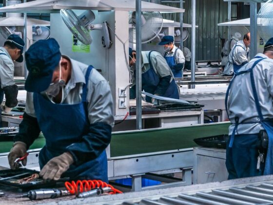 Pessoas fazendo produção de veículos em fábrica.