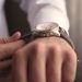 a man puts on a watch nv hand.