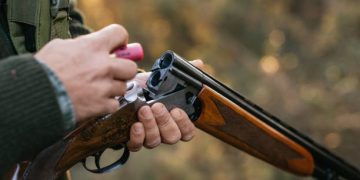 Hunter man loading his gun while hunting outdoors. Hunting season concept.