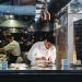 A chef is cooking in his restaurant's kitchen. Shot through the glass. High-end gourmet restaurant.