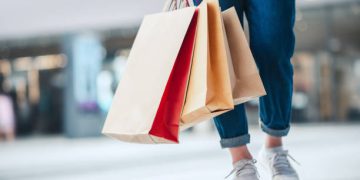 Closeup - Woman holding sale shopping bags. Consumerism, shopping, lifestyle concept