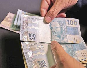 Notas de cem reais nas mãos de um homem