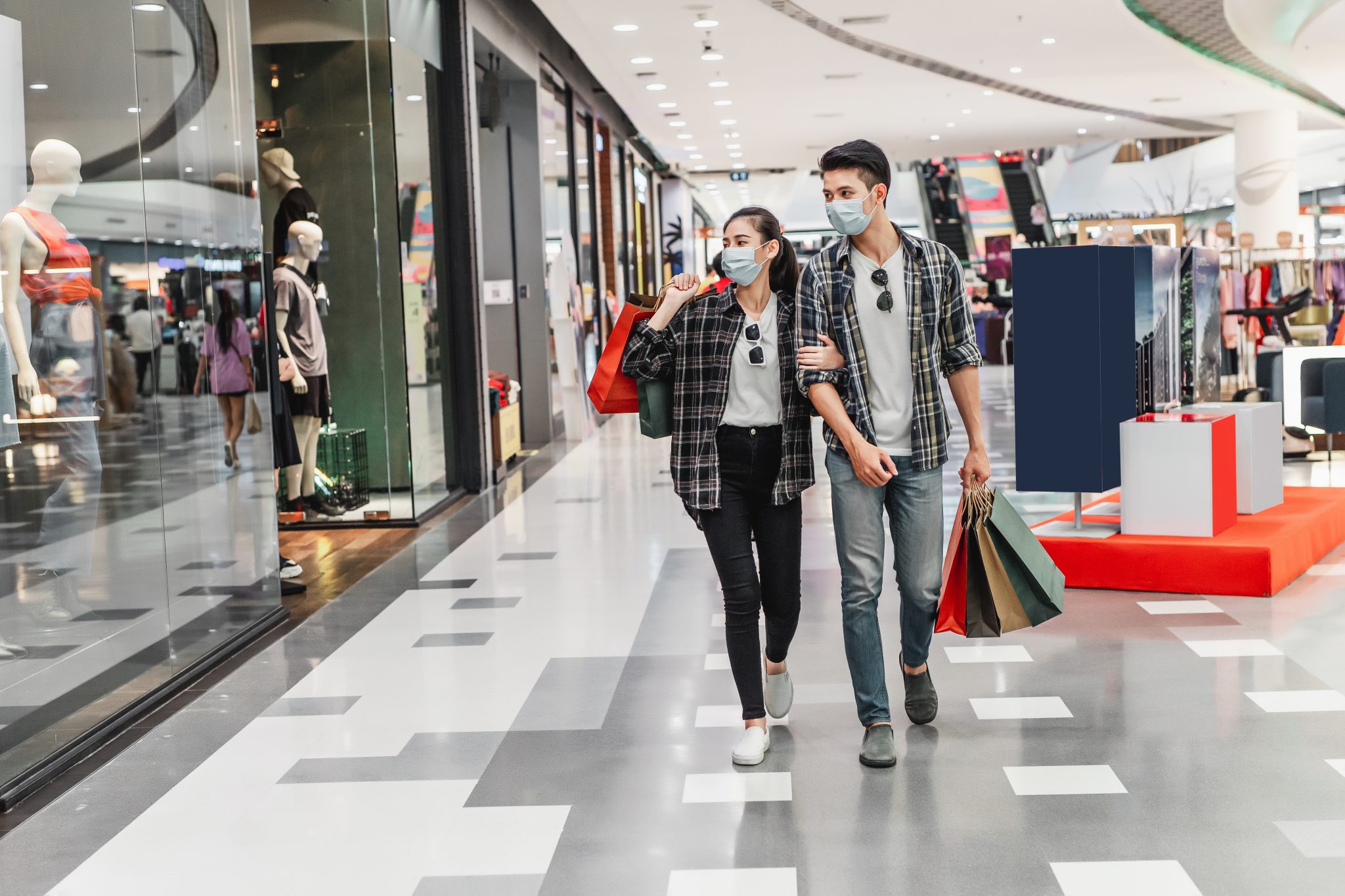Young couple holding multiple shopping paper bag at mall