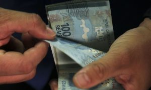 Pessoa contando notas de cem reais