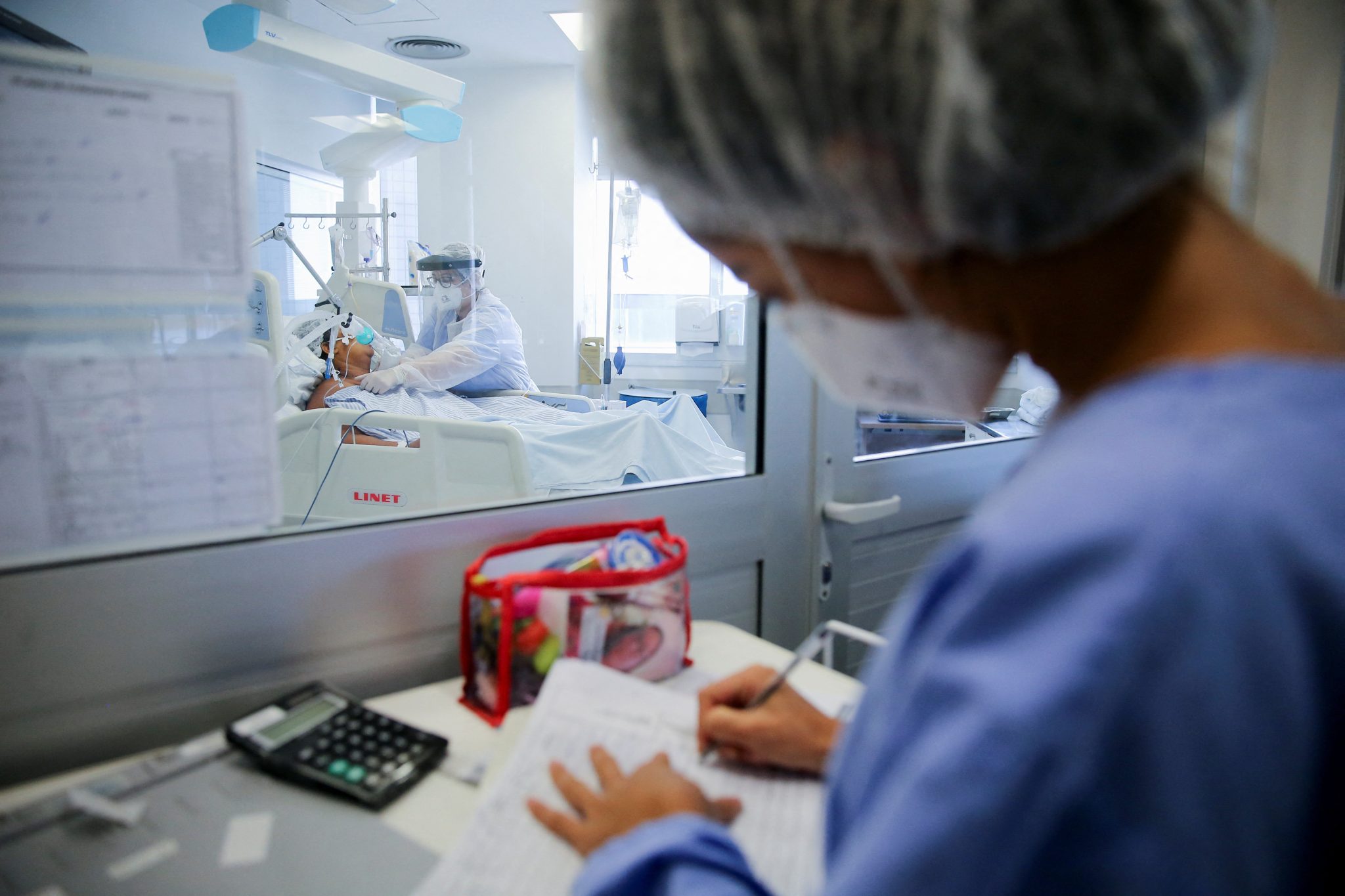 Profissional em hospital de máscara e toca faz anotações em uma folha