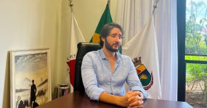 gabriel azevedo com as mãos cruzadas sob uma mesa de madeira