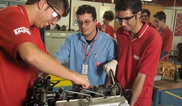 tres homens estao em volta de uma maquina com ferramentas na mao