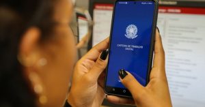 Mulher com celular na mão com o aplicativo da carteira de trabalho digital na tela