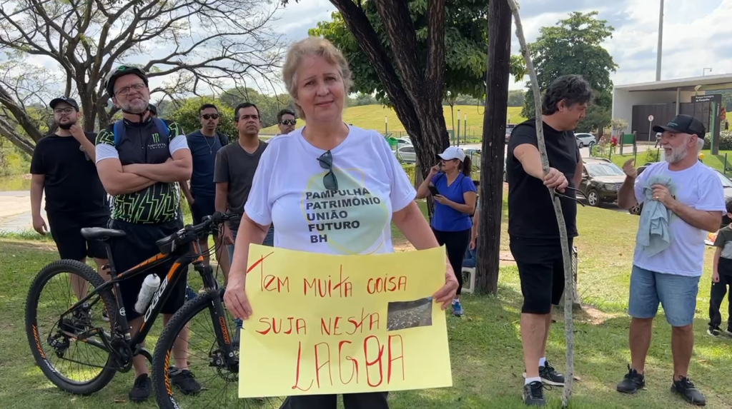uma manifestante segurando cartaz escrito: tem muita coisa suja nesta lagoa.