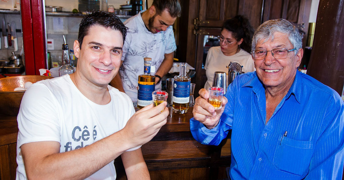 Daniel Duarte e o pai, Adão, da Flor das Gerais, saboreiam a medalha de ouro, a cachaça Flor das Gerais Amburana | Crédito: Divulgação/Cachaçaria Flor das Gerais