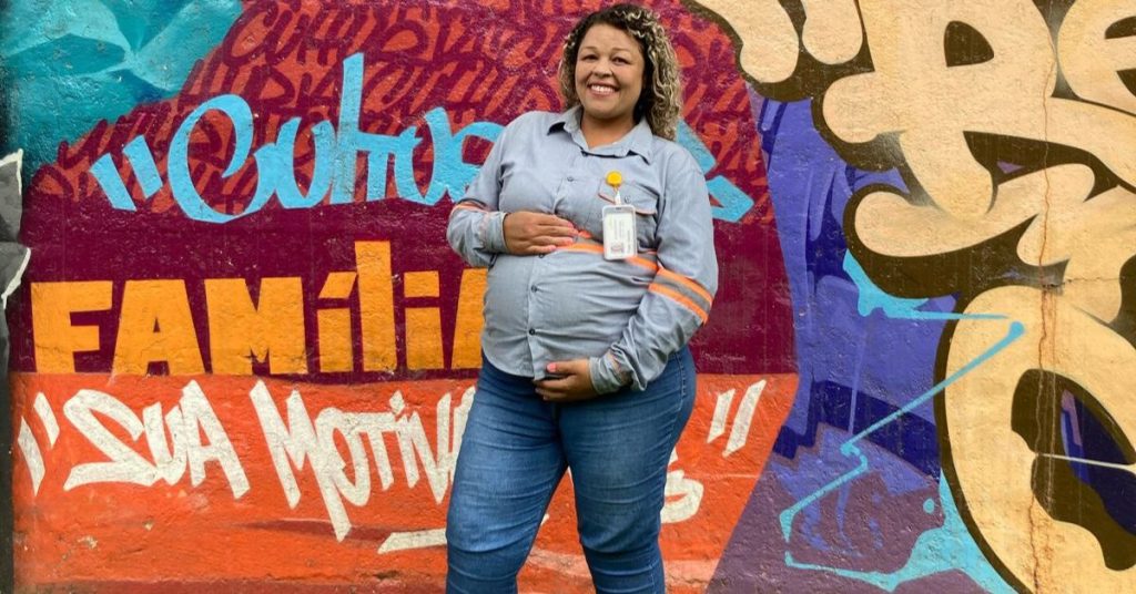 Mulher grávida em frente a um painel colorido