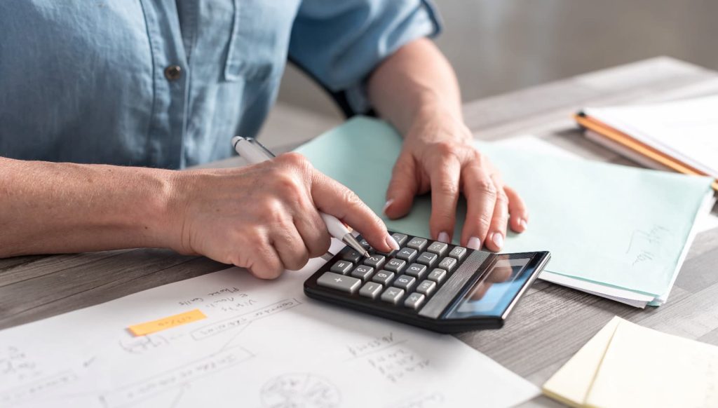 Pessoa com fazendo cálculos em uma calculadora
