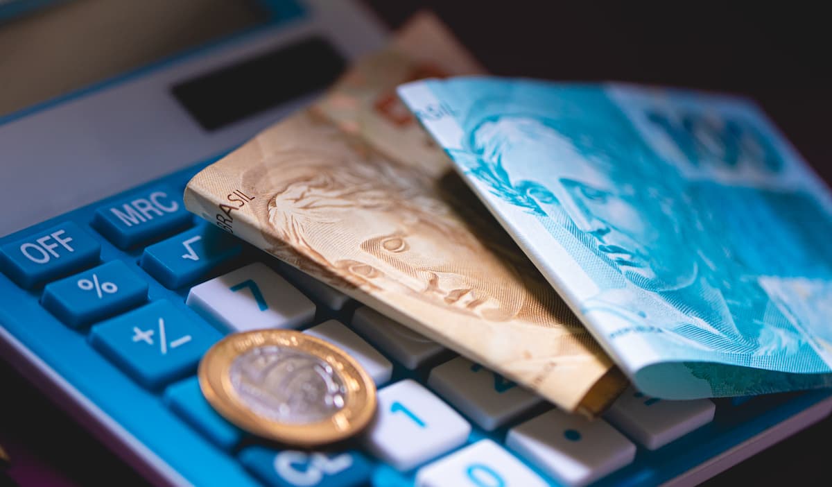 Calculadora, notas de 100 e 50 e uma moeda